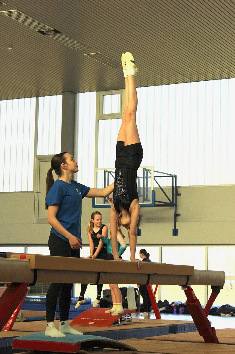 Trainerin Nina Klöppel hält einen Handstand am Schwebebalken
